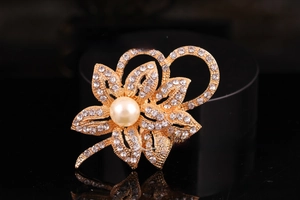 Detailed close-up of a flower brooch featuring white rhinestones and a large cream pearl