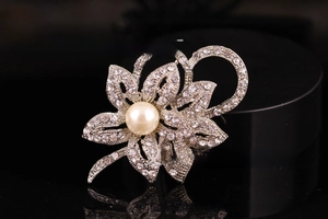 Macro detail of silver flower brooch with sparkling rhinestones and a large center pearl