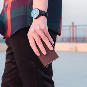 Detailed view of a brown leather pop-up card holder wallet on a scenic terrace background