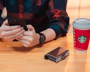 Lifestyle view of a brown PU leather pop-up card wallet and metal case on a wooden table