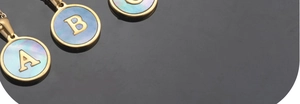 Detail view of 18K gold plated A-Z letter pendants with blue shell inlay and metal border