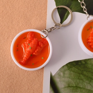 Realistic PVC mini crayfish bowl keychain with red oil detail on a textured background