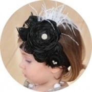 Detail of children headband featuring a black floral design with white feathers and pearls