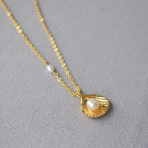 Macro view of gold shell pendant necklace with lustrous white freshwater pearl detail
