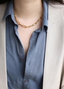 Polished gold paperclip chain necklace worn with a blazer for a modern minimalist style