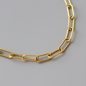 Detailed close-up of chunky gold-plated paperclip chain link necklace with a polished finish