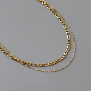 Detail view of double-layer gold titanium steel Figaro chain necklace with layered textures