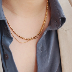 Detail view of double-layered gold stainless steel Figaro chain necklace on a model