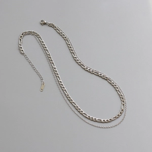 Detail of silver double-layered Figaro and curb chain necklace with lobster clasp and extension