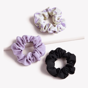 Set of three satin hair scrunchies in lavender floral, plain purple, and black colors