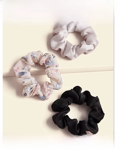 Three-piece scrunchie set featuring floral, purple pleated and black satin fabrics