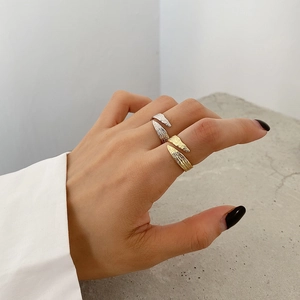 Macro shot of minimalist textured silver and gold adjustable rings on model fingers