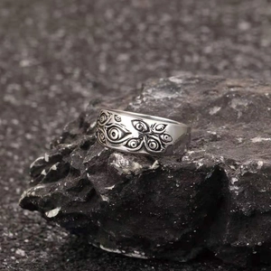 Detailed close-up of gothic silver evil eye ring placed on a dark volcanic rock