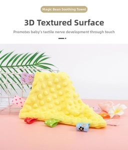 Macro detail of yellow baby comforter featuring 3D tactile nubs and colorful ribbon tags