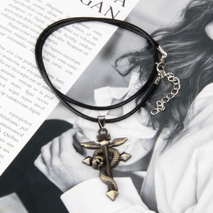 Close-up of a vintage gothic cross sword necklace with a snake wrap on a book