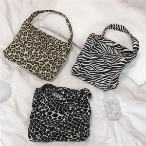 Flat lay detail of leopard and zebra print canvas shoulder bags with magnetic button closure