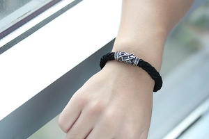 Nahaufnahme eines geflochtenen Lederarmbands mit Vintage-Totem-Metallperle am Handgelenk