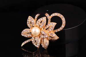 Detail of silver floral brooch featuring large white pearl and sparkling rhinestones