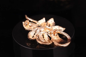 Detailed back view of flower brooch with metal texture and horizontal safety pin clasp
