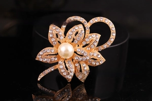 Macro shot of silver flower brooch with sparkling rhinestones and a large pearl center