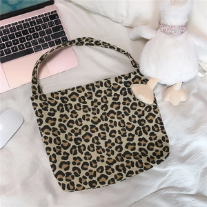 Detail shot of leopard print canvas tote bag on bed with lifestyle accessories