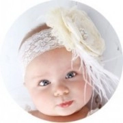 Detail of white lace baby headband with large silk flower and soft feather accents