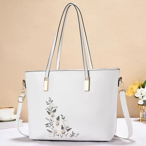 Borsa tote bianca con ricamo floreale e hardware dorato, presentata con eleganza