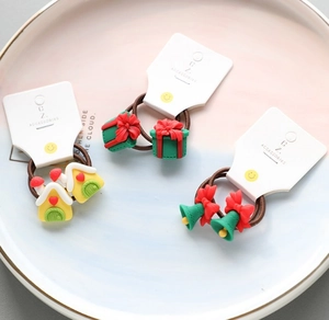 Close-up of festive gingerbread house and gift box hair ties in a pink ceramic tray