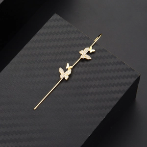 Detailed view of gold butterfly ear climbers with cubic zirconia on black carbon fiber
