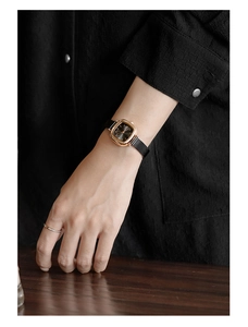 Close-up of minimalist square women's watch with black dial and gold mesh band