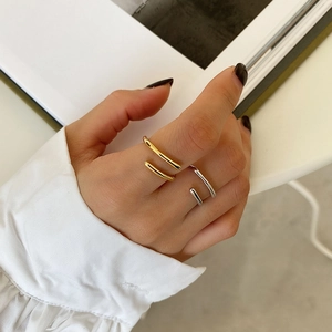 Close-up of minimalist layered open rings in gold and silver finish worn on fingers