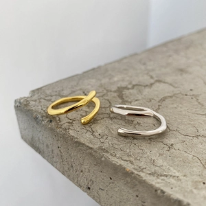 Detail of adjustable minimalist silver and gold rings on a textured stone surface