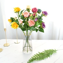 Detail of colorful artificial silk roses in a glass vase for home interior decoration