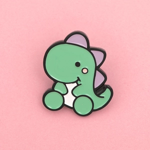 Close-up of a cute green dinosaur enamel pin with purple spikes on pink background