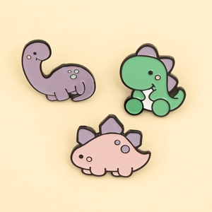 Detail view of cute pastel enamel pins featuring purple, green, and pink dinosaur designs