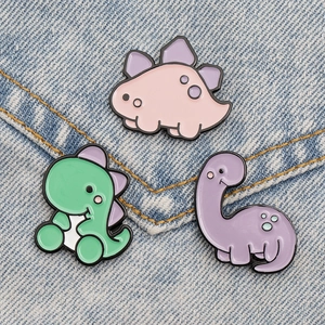 Close-up of cute candy-colored dinosaur enamel pins on blue denim fabric background