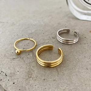 Minimalist gold and silver layered open rings displayed on a modern stone surface