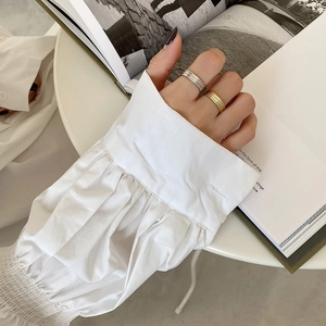 Minimalist gold and silver ribbed stackable rings worn over an open book for aesthetic style