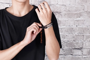 Detail of multi-layer black leather bracelet with stainless steel razor blade charm on wrist