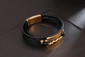 Macro shot of multi-layer black leather bracelet with golden razor blade charm and magnetic clasp