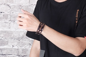Detail of dark brown multi-layer braided leather bracelet with vintage metal razor blade