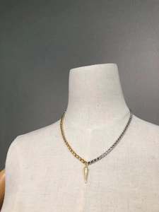 Detail of two-tone gold and silver chain necklace with a sharp gold cone pendant