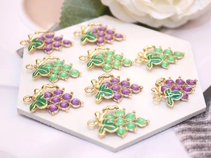 Detailed close-up of grape-shaped alloy charms for DIY necklaces on a white stand