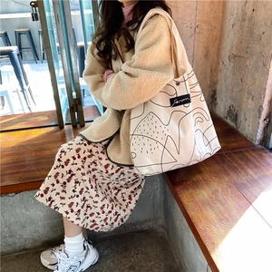 Detail of canvas tote bag with abstract art print and woven label on a casual day outfit
