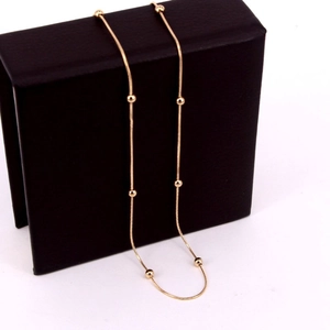 Detailed close-up of rose gold bead snake chain necklace on black jewelry box display