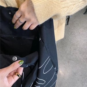 Detail of black canvas tote showing secure magnetic snap button and inner zipper pocket