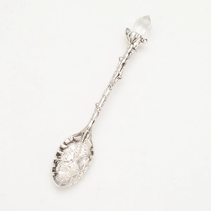 Vintage silver coffee spoon with crystal tip and leaf pattern on white background