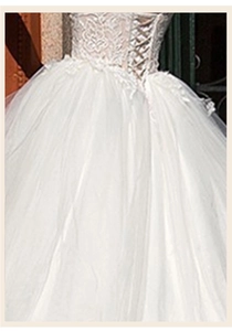 Detailed close-up of lace patterns and waist drawstring on a white wedding dress