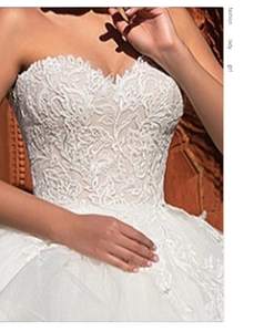 Close-up of white sweetheart bridal gown featuring intricate floral lace and mesh layers