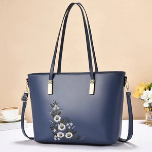Dettaglio borsa tote blu scuro con ricamo floreale bianco e finiture metalliche dorate